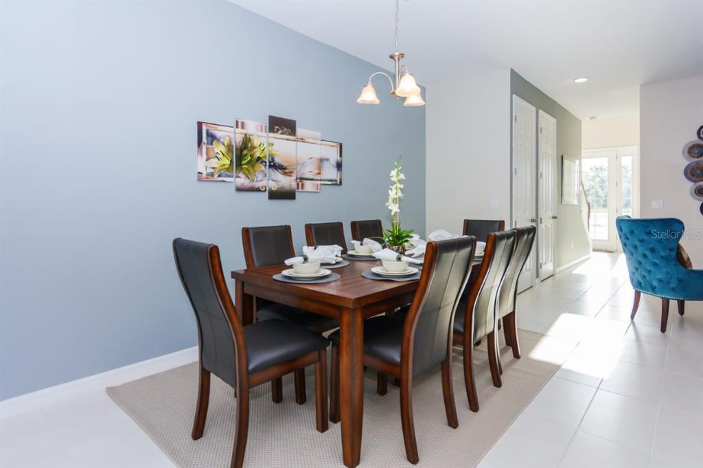 A dining room features a wooden table with six chairs under a light fixture — 1534 CAREY PALM CIRCLE, KISSIMMEE, FL