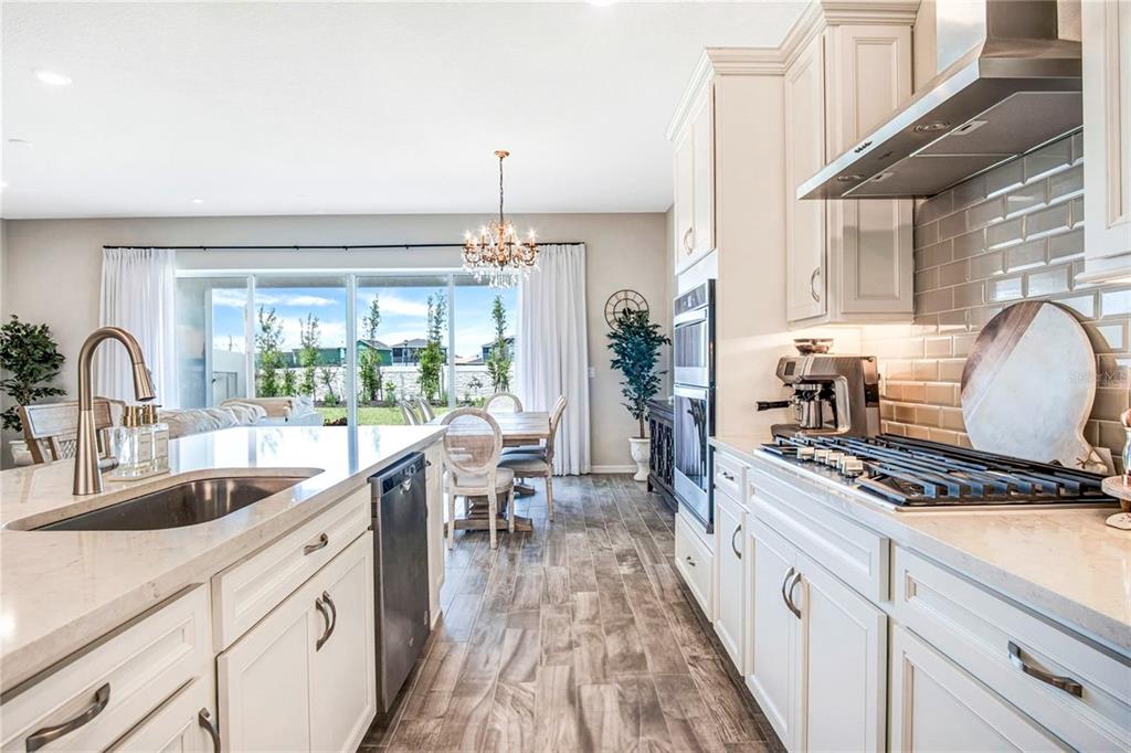 A kitchen with white cabinets, a large island, and a dining area overlooking a backyard — 13348 PANAMA BEACH COURT, ORLANDO, FL