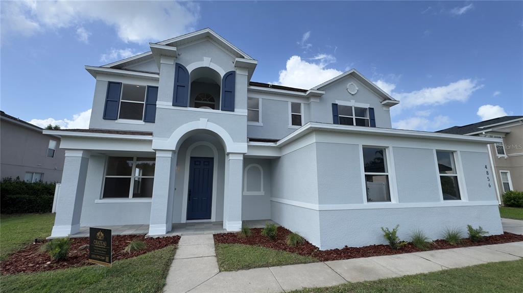 A two-story light blue house features a dark blue front door and matching window shutters — 4856 STONE ACRES CIRCLE, ST CLOUD, FL
