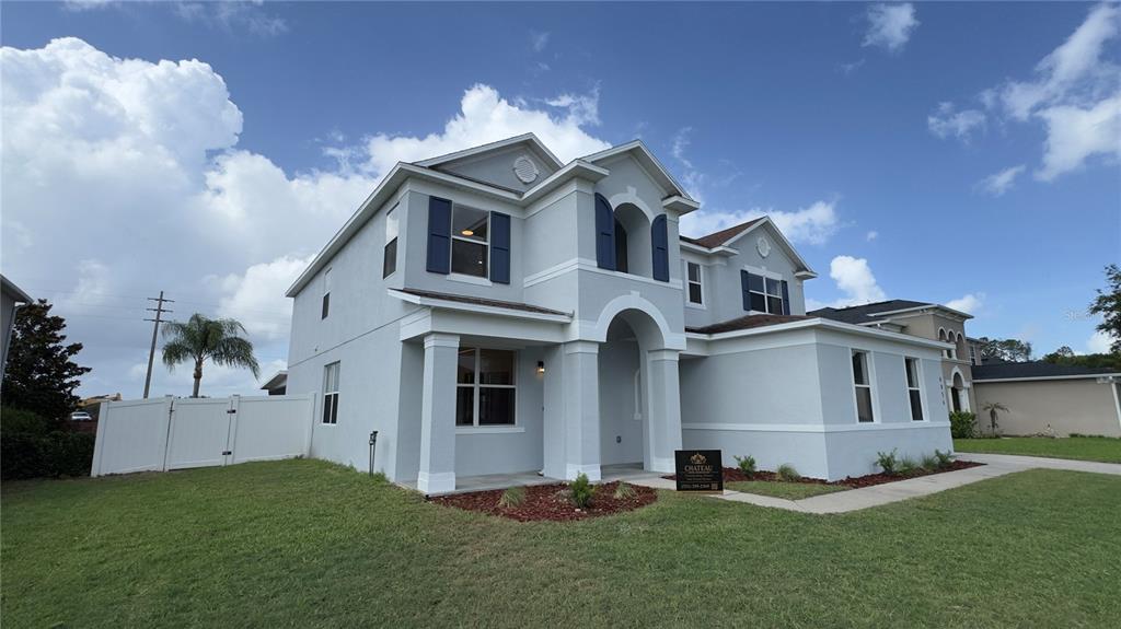 A two-story light gray house with blue shutters and a white fence under a sky — 4856 STONE ACRES CIRCLE, ST CLOUD, FL