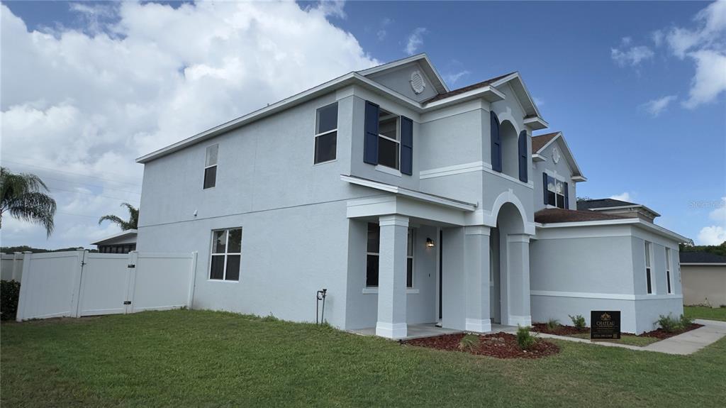 A two-story house with light gray stucco siding, blue shutters, and a white vinyl fence — 4856 STONE ACRES CIRCLE, ST CLOUD, FL