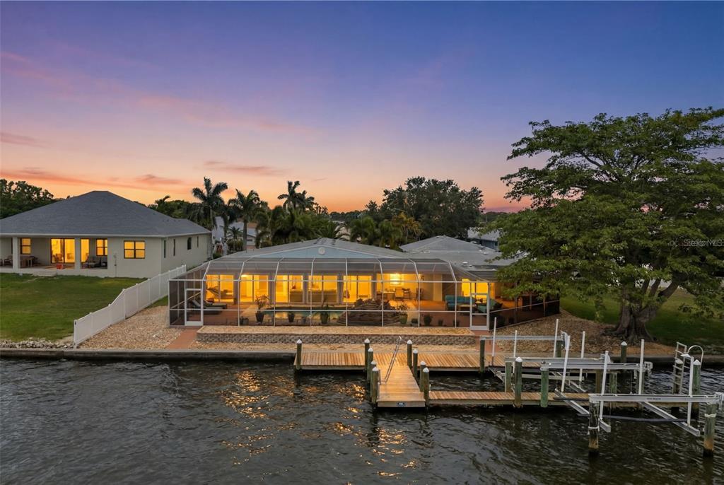 An aerial view of a waterfront house with a screened-in pool and a private dock — 604 POINSETTIA AVENUE, ELLENTON, FL