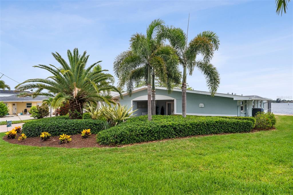 A single-story house with a palm tree, manicured hedges, and a grassy lawn — 604 POINSETTIA AVENUE, ELLENTON, FL