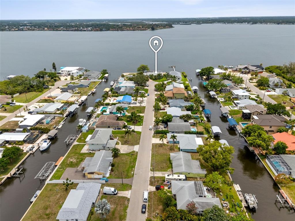 An aerial view shows a residential street lined with houses and private boat docks — 604 POINSETTIA AVENUE, ELLENTON, FL