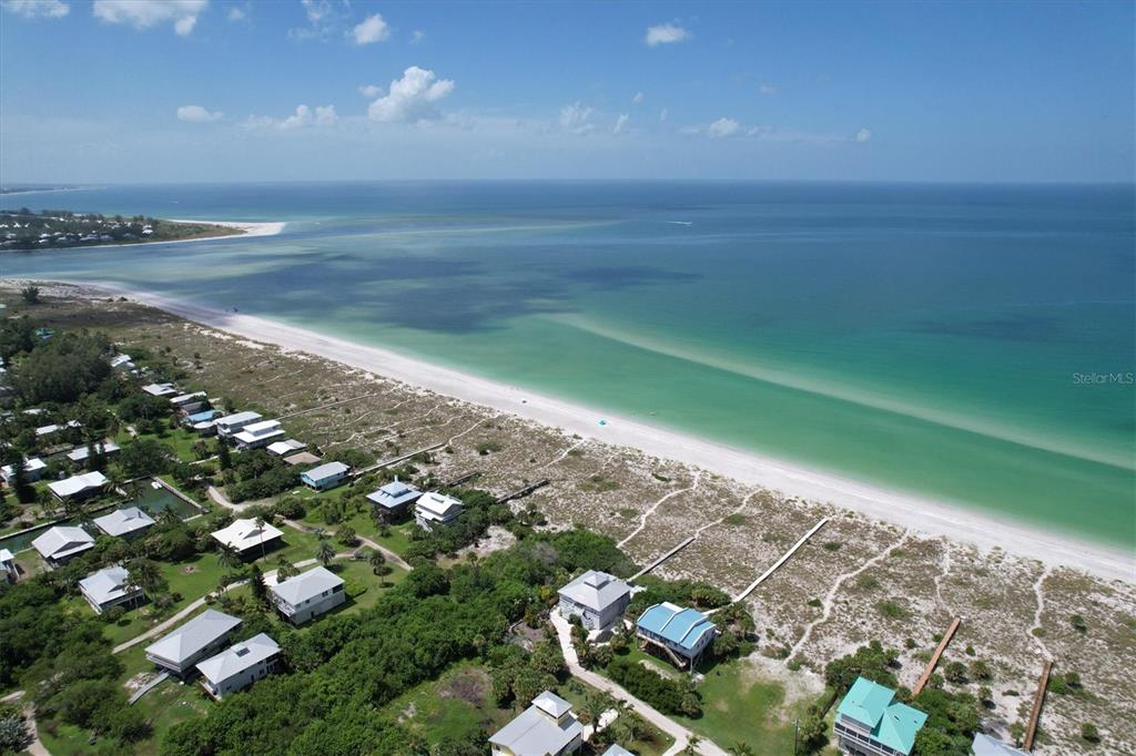 An aerial view shows beach houses nestled among trees along a sandy coastline and ocean — 9736 LITTLE GASPARILLA ISLAND UNIT B, PLACIDA, FL