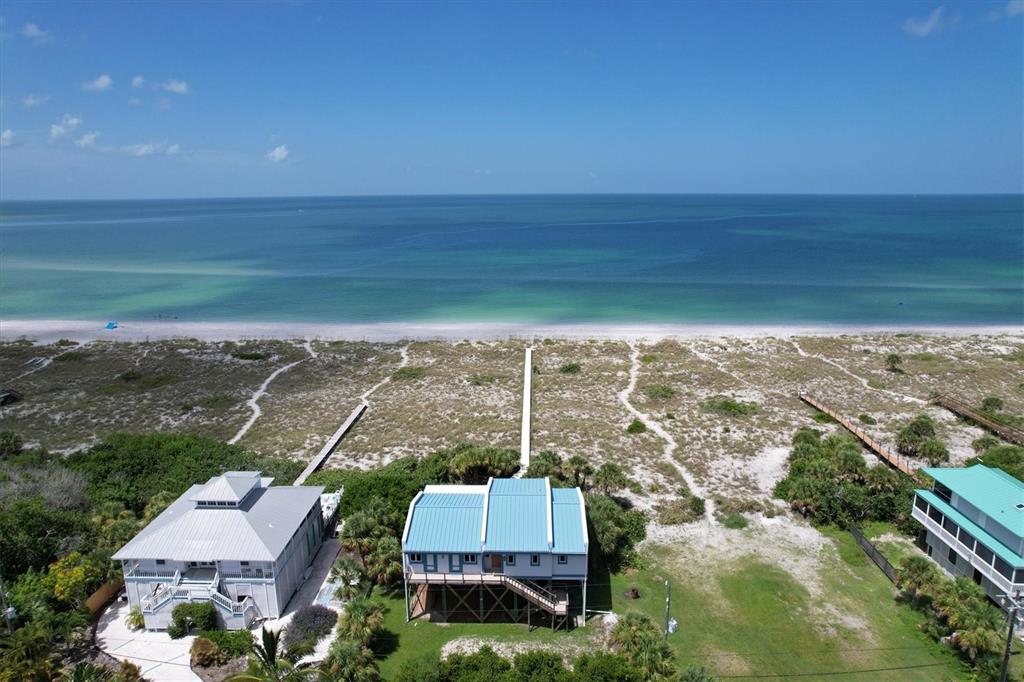 An aerial view shows two beachfront houses with metal roofs and private walkways to the beach — 9736 LITTLE GASPARILLA ISLAND UNIT B, PLACIDA, FL