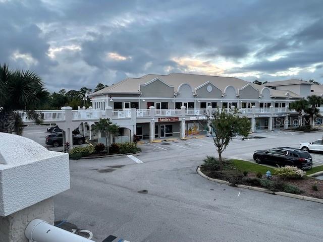 An exterior view of a multi-story commercial building with a parking lot in front — 160 CYPRESS POINT PARKWAY UNIT C212, PALM COAST, FL