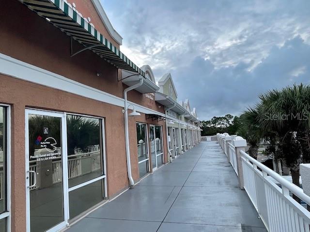 A view of a commercial building exterior with a covered walkway and glass storefronts — 160 CYPRESS POINT PARKWAY UNIT C212, PALM COAST, FL
