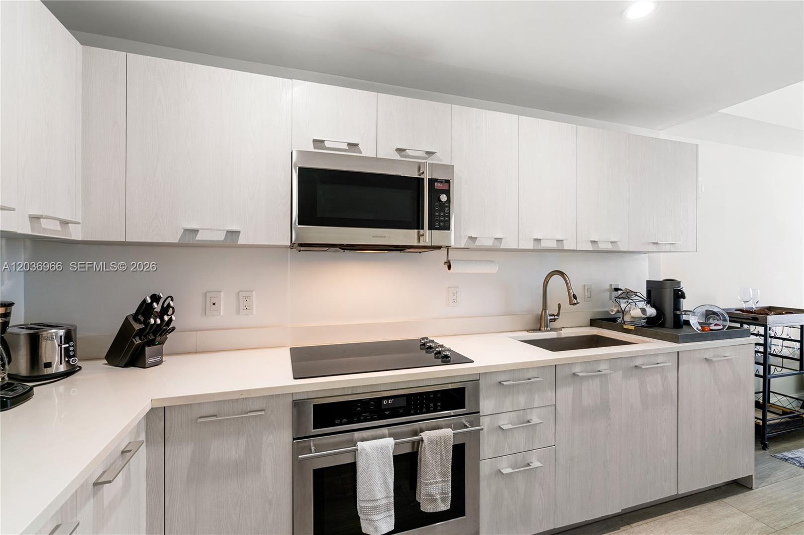 A modern kitchen features light wood-grain cabinets, stainless steel appliances, and white countertops — 55 SW 9th St # 1904, Miami FL 33130, MIAMI, FL
