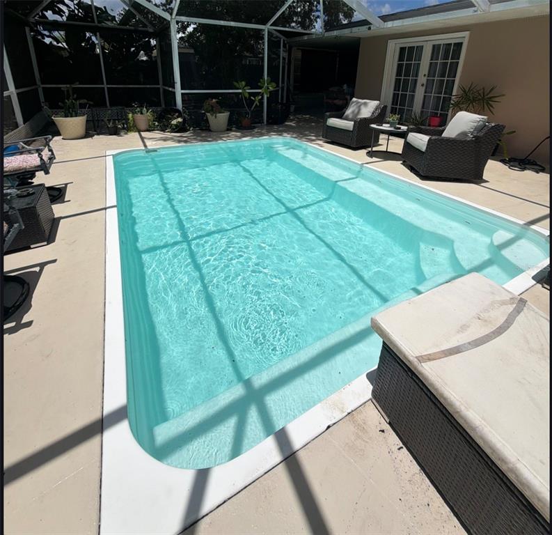 A covered patio features a dining table, a sofa, a ceiling fan, and a screened enclosure — 8093 HERBISON AVENUE, NORTH PORT, FL
