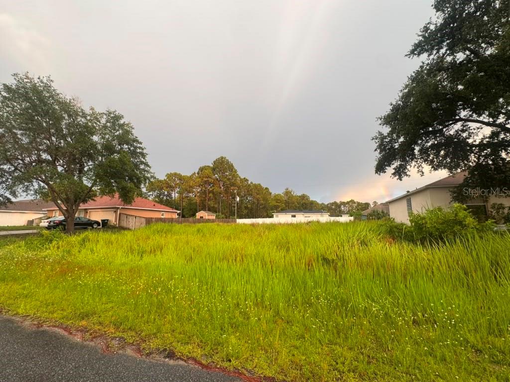 A grassy vacant lot sits between two suburban houses under a cloudy sky — 612 GAGNON STREET SE, PALM BAY, FL