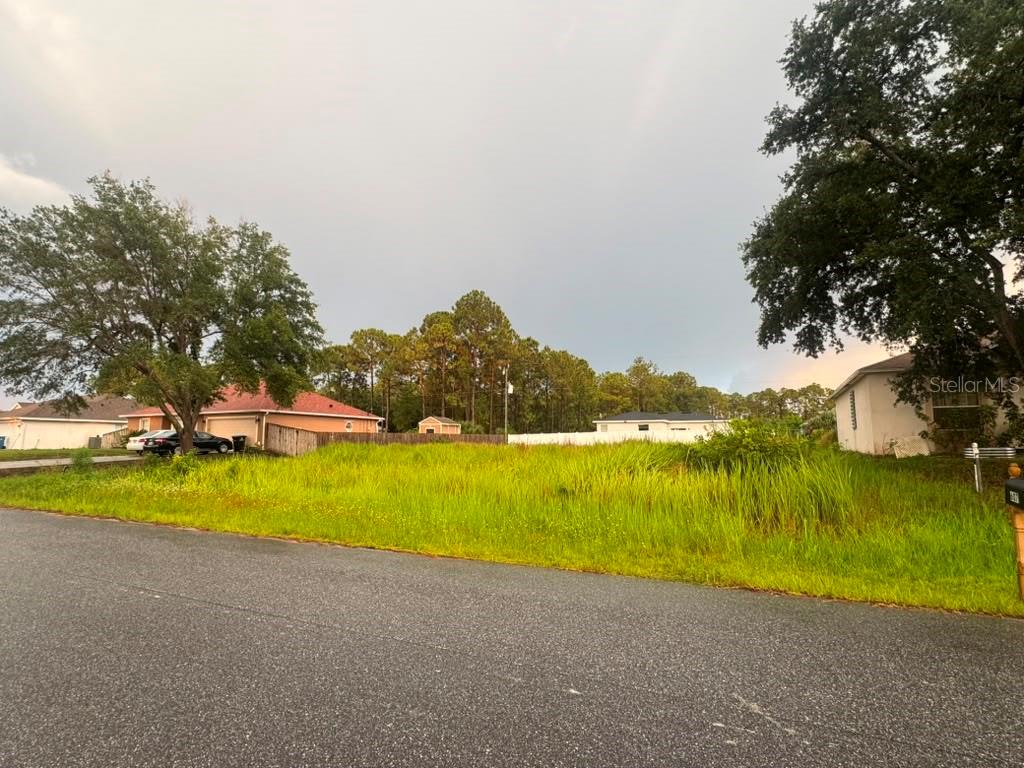 A vacant, grassy residential lot sits between two houses under a cloudy sky — 612 GAGNON STREET SE, PALM BAY, FL