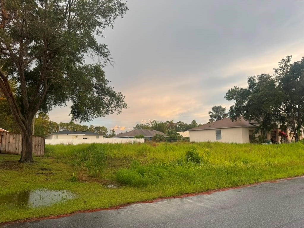 A vacant, grassy residential lot sits between two houses under a cloudy sky — 612 GAGNON STREET SE, PALM BAY, FL