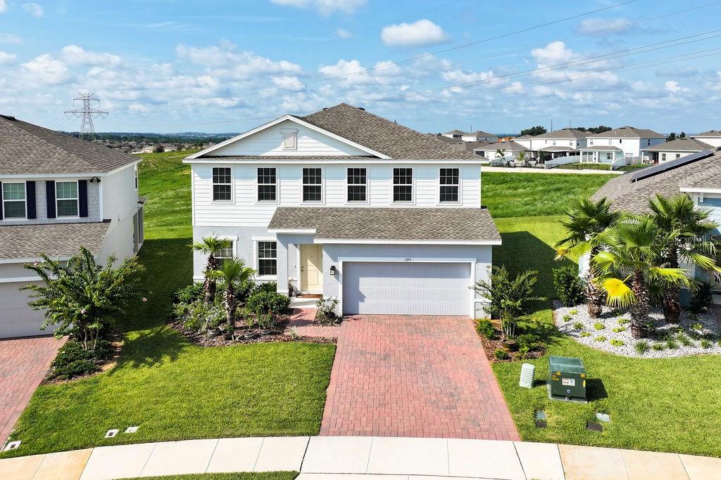 An aerial view of a two-story suburban house with a brick driveway and green lawn — 1193 WHISPERING LANE, MINNEOLA, FL