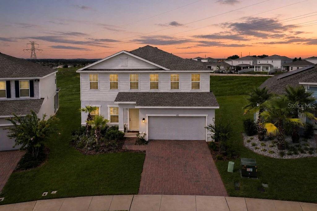 An aerial view of a two-story suburban house with a brick driveway and garage — 1193 WHISPERING LANE, MINNEOLA, FL