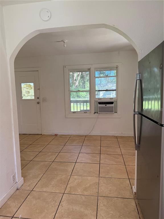 A kitchen with tan tile flooring, an arched doorway, and a window air conditioning unit — 5976 SE 115TH STREET, BELLEVIEW, FL