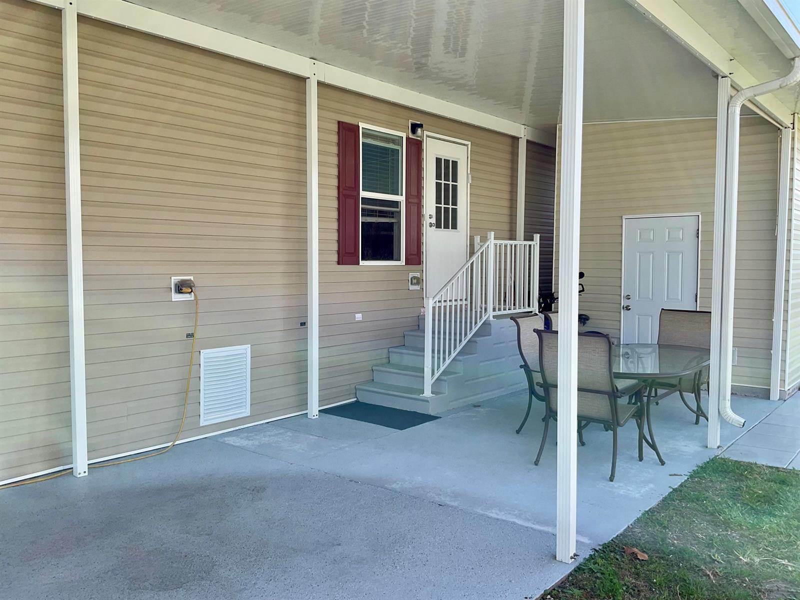 A covered concrete patio features a set of stairs leading to a white entry door — 106 Sandhill Boulevard, Fort Pierce FL 34982, FORT PIERCE, FL