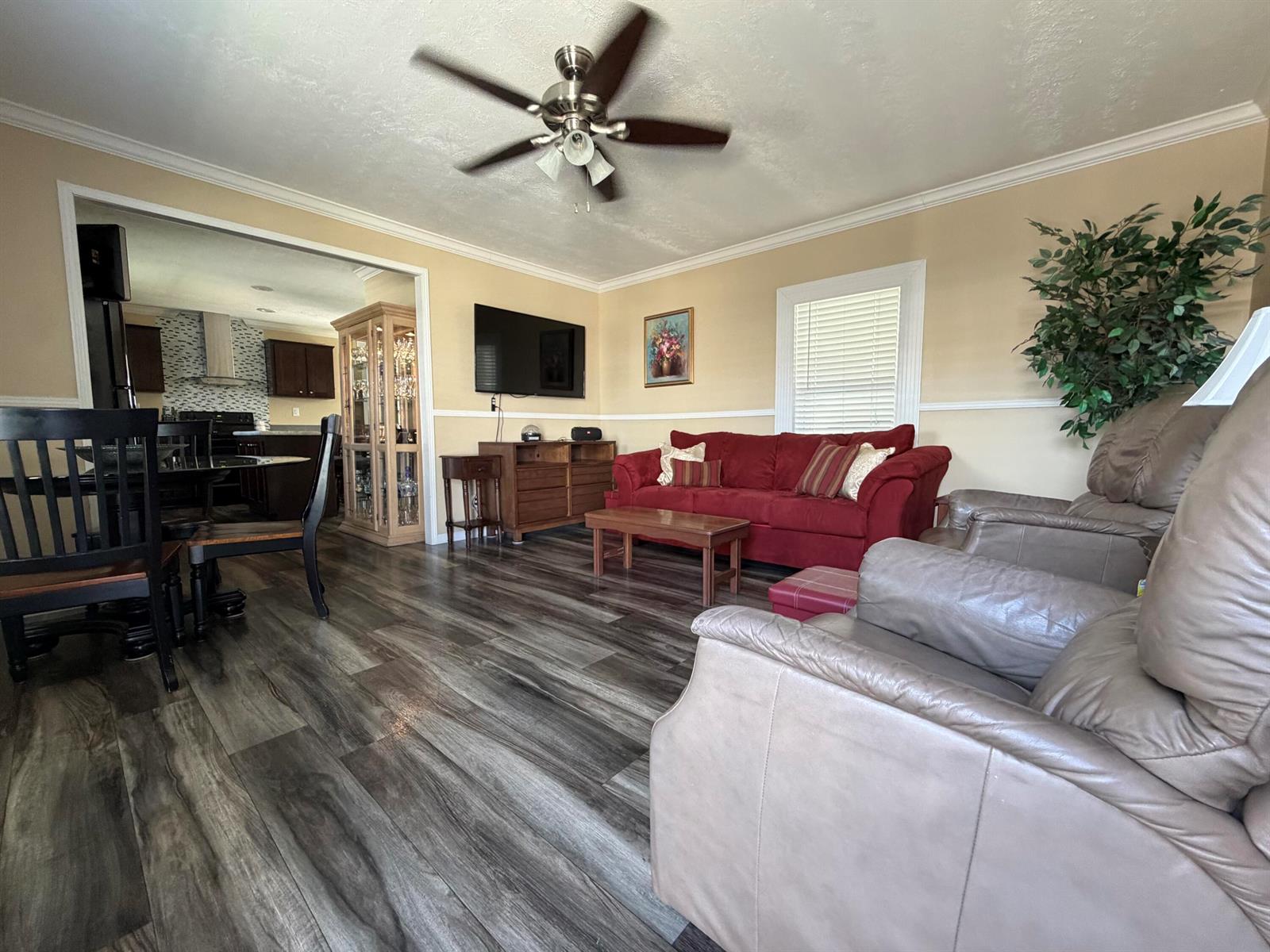 A living room features wood-look flooring, a red sofa, leather recliners, and a ceiling fan — 106 Sandhill Boulevard, Fort Pierce FL 34982, FORT PIERCE, FL