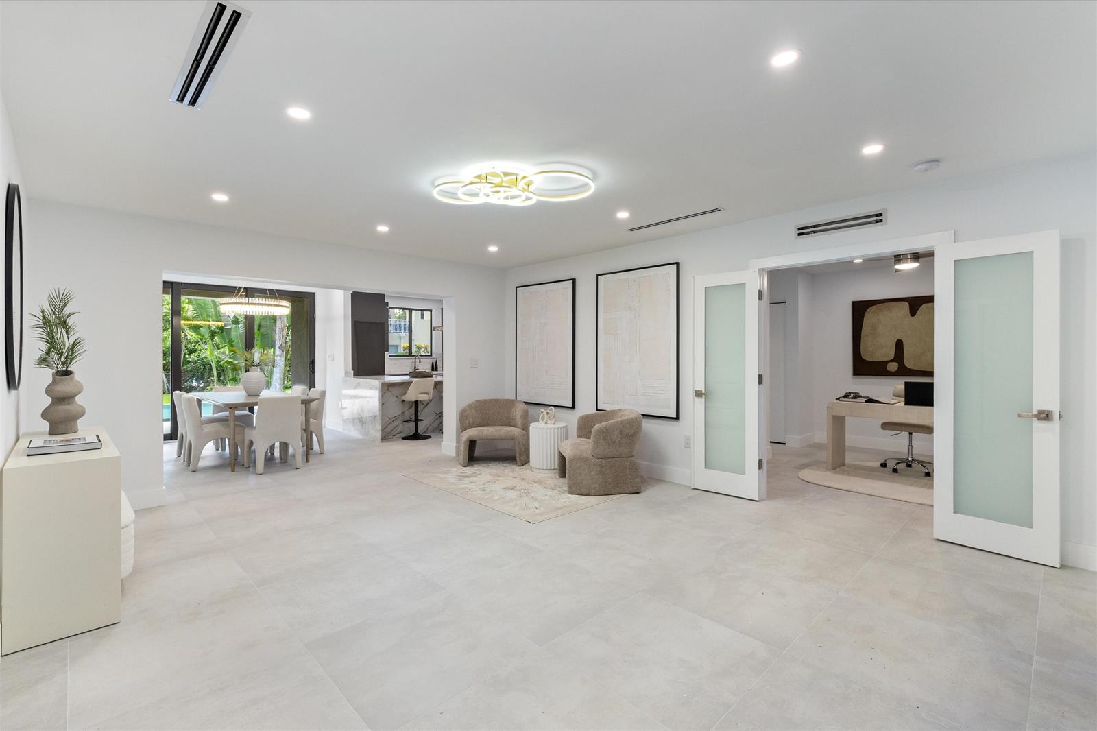 A bright, open-concept living area with white tile floors, modern lighting, and an adjacent office — 451 NE 119th Street, Biscayne Park FL 33161, BISCAYNE PARK, FL