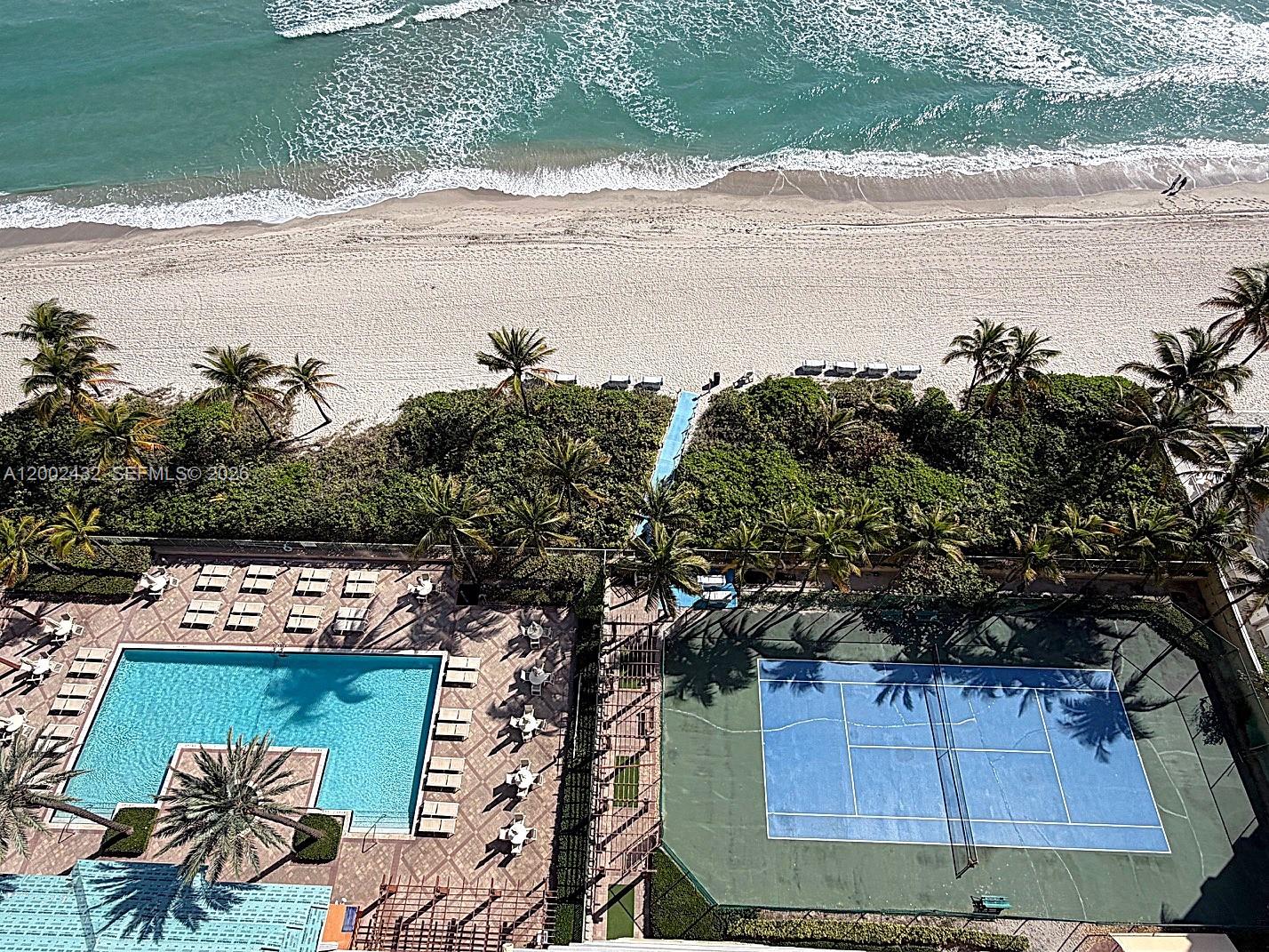 An aerial view shows a swimming pool, a tennis court, and a beach with palm trees — 2080 S Ocean Dr, Hallandale Beach FL 33009, HALLANDALE BEACH, FL