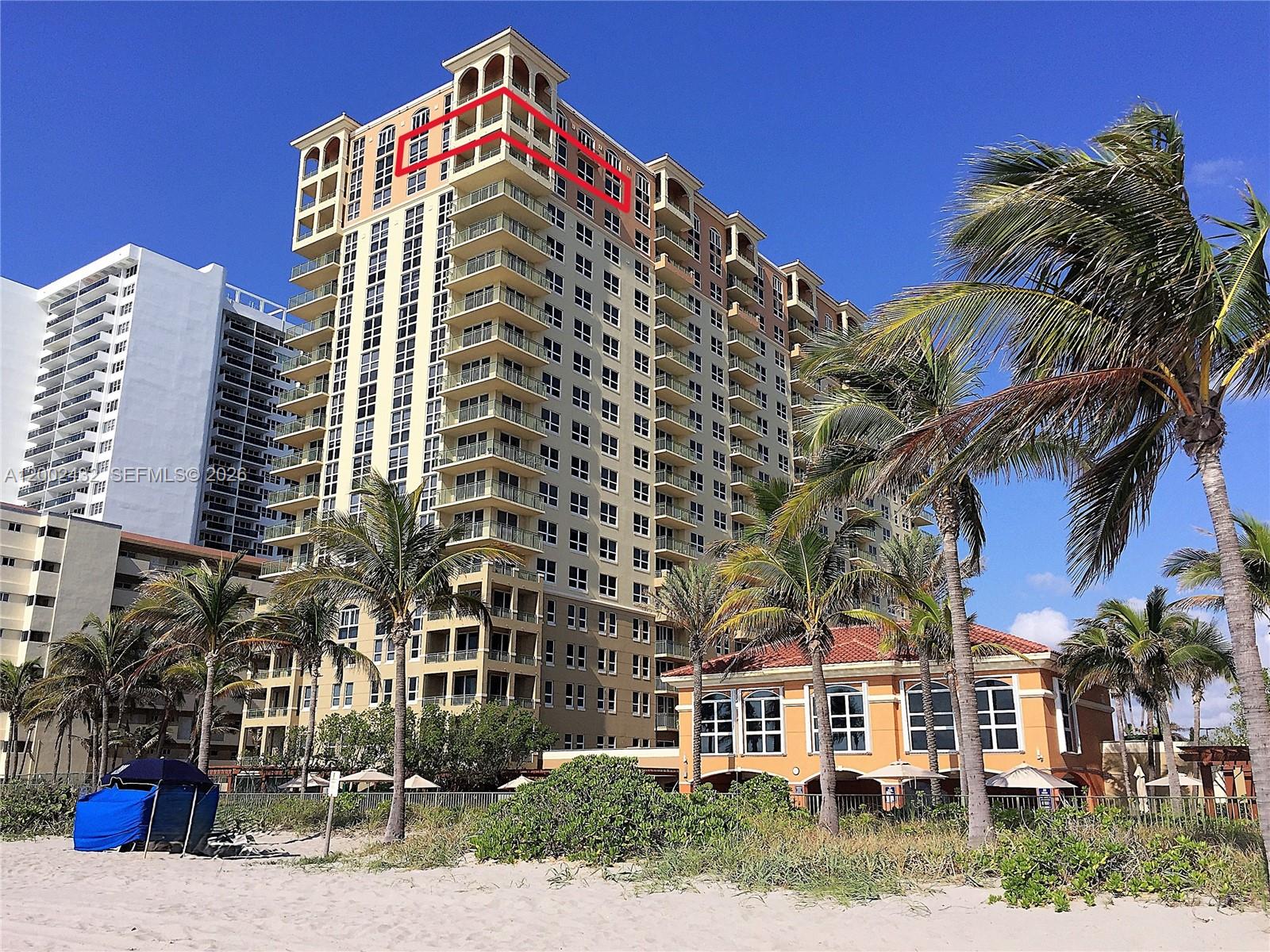 A tall, multi-story residential building with balconies stands near a sandy beach with palm trees — 2080 S Ocean Dr, Hallandale Beach FL 33009, HALLANDALE BEACH, FL
