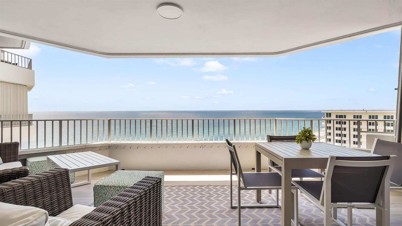 A balcony with outdoor furniture overlooks the ocean and a neighboring building — 550 S Ocean Boulevard # 1906, Boca Raton FL 33432, BOCA RATON, FL