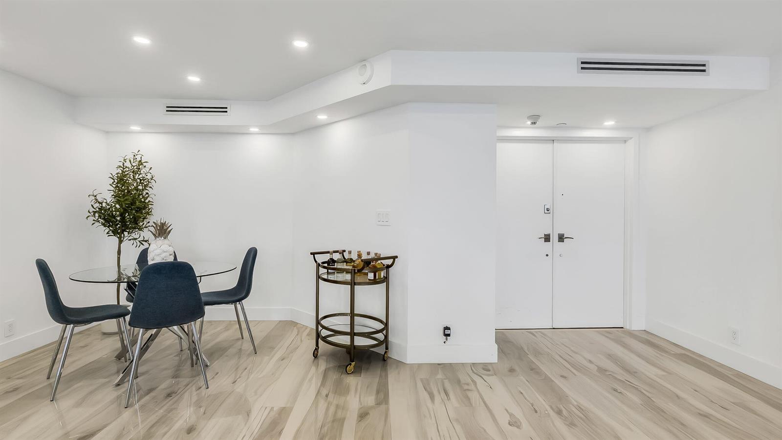 A dining area with a glass table and bar cart sits near a white door — 550 S Ocean Boulevard # 1906, Boca Raton FL 33432, BOCA RATON, FL