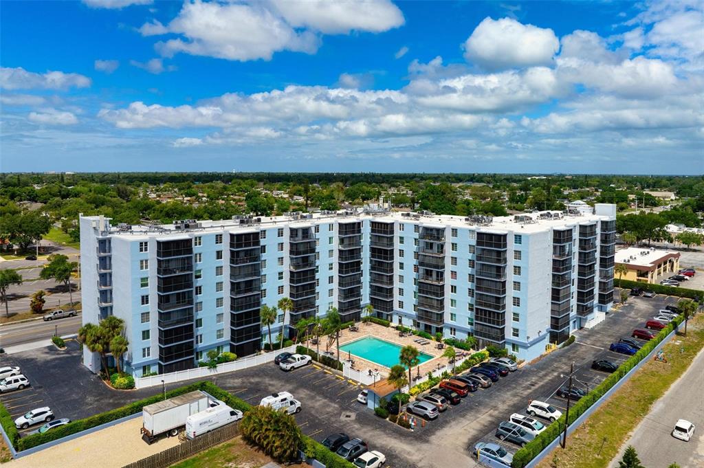 An aerial view of a multi-story apartment building with a swimming pool and parking lot — 2901 26TH STREET W UNIT 303, BRADENTON, FL