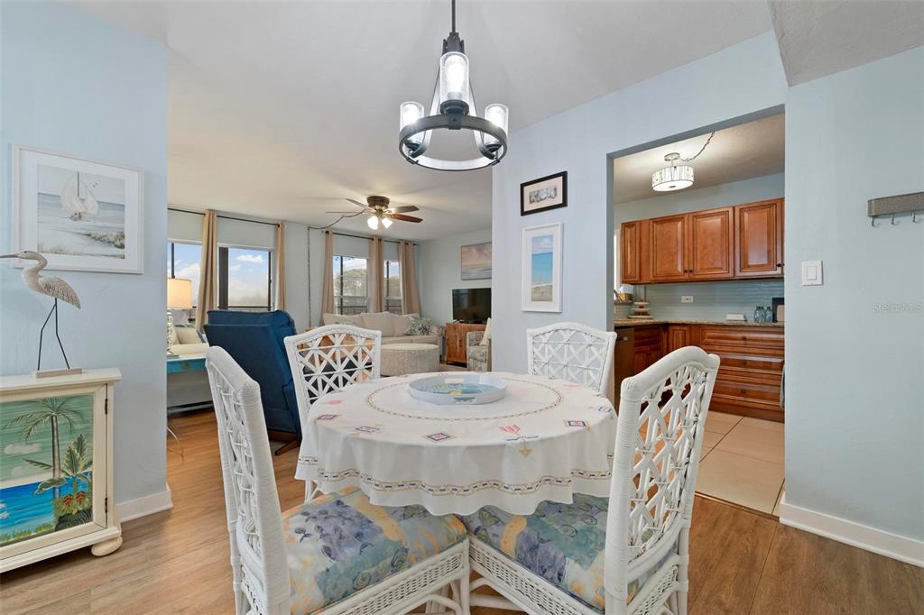 A dining area with a round table and chairs opens into a living room and kitchen — 2901 26TH STREET W UNIT 303, BRADENTON, FL