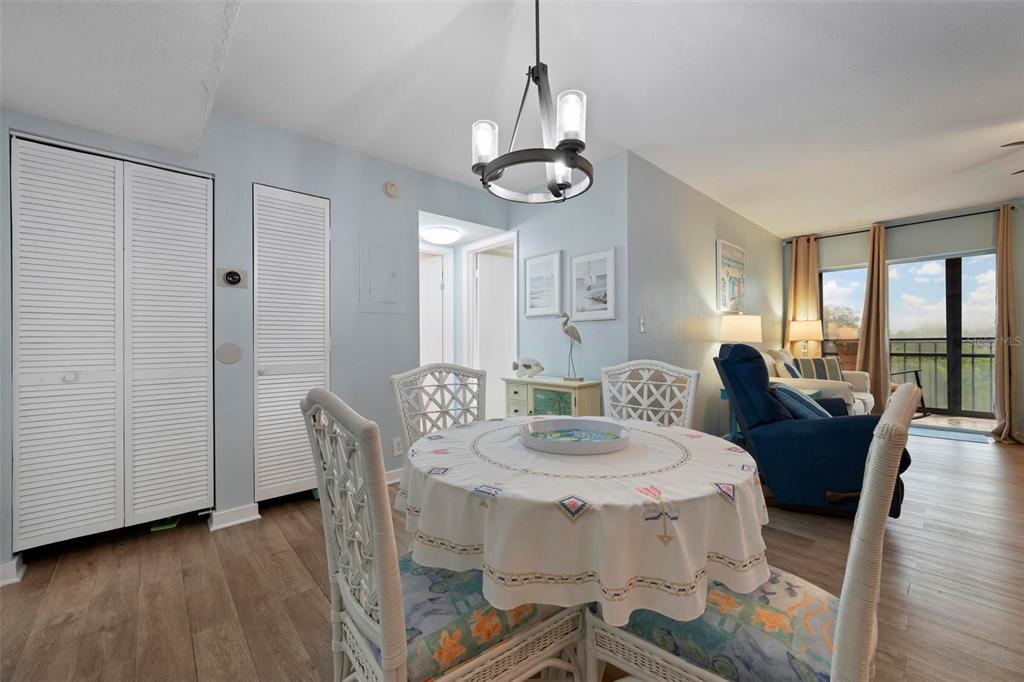 A dining area with a round table, wicker chairs, and a chandelier, opening to a living room — 2901 26TH STREET W UNIT 303, BRADENTON, FL