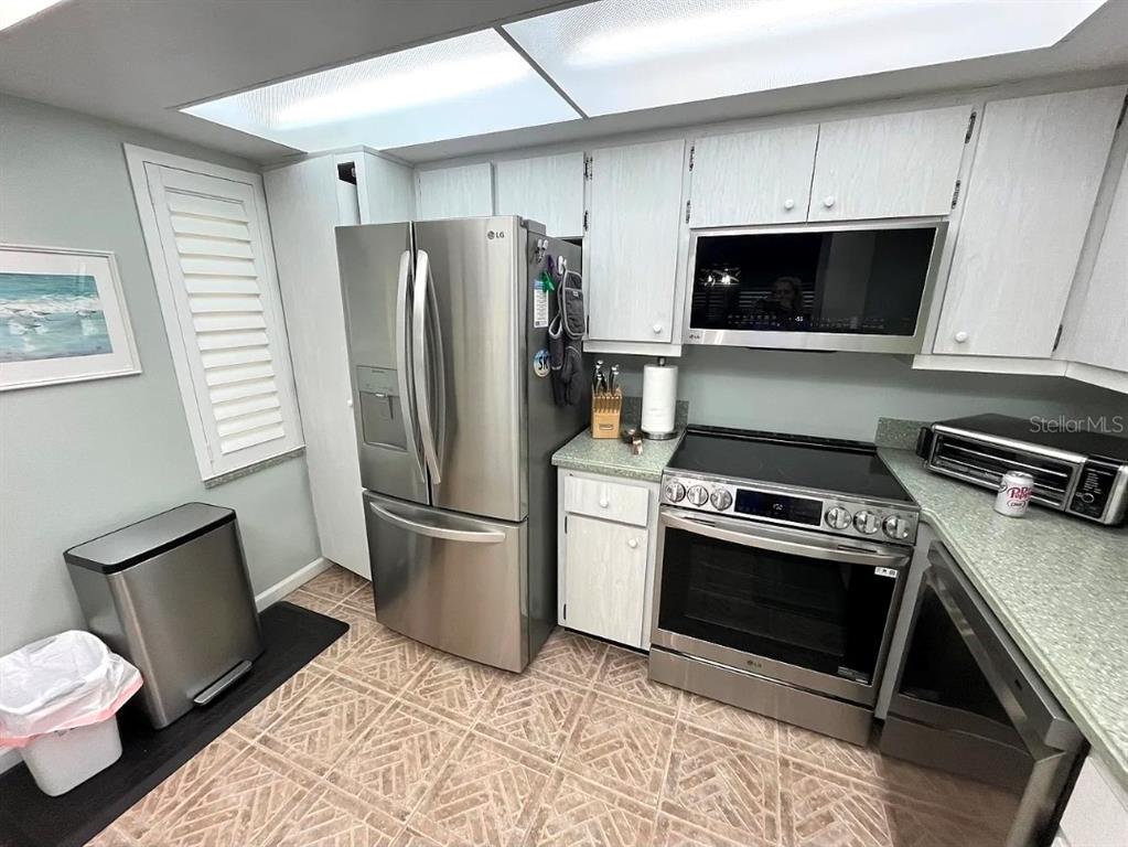 A kitchen features stainless steel appliances, light-colored cabinets, and patterned tile flooring — 1250 N PORTOFINO DRIVE UNIT 301, SARASOTA, FL