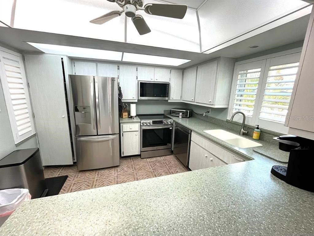 A kitchen features stainless steel appliances, light-colored cabinetry, and a green speckled countertop — 1250 N PORTOFINO DRIVE UNIT 301, SARASOTA, FL