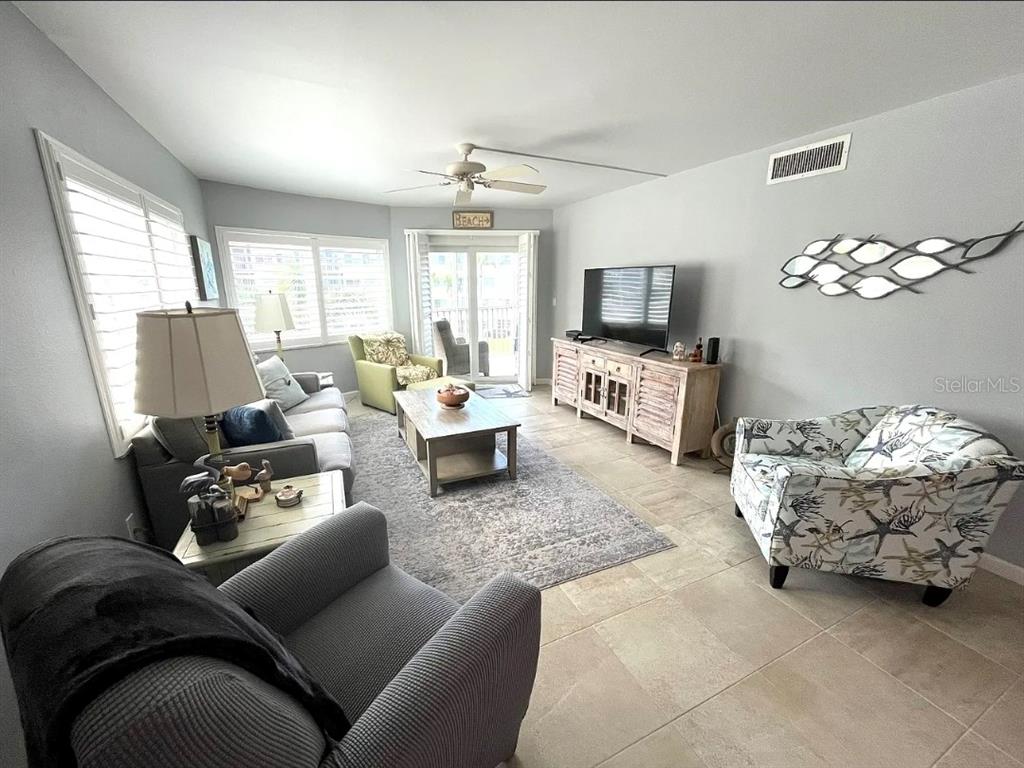 A living room features tile flooring, a gray area rug, a television console, and seating — 1250 N PORTOFINO DRIVE UNIT 301, SARASOTA, FL