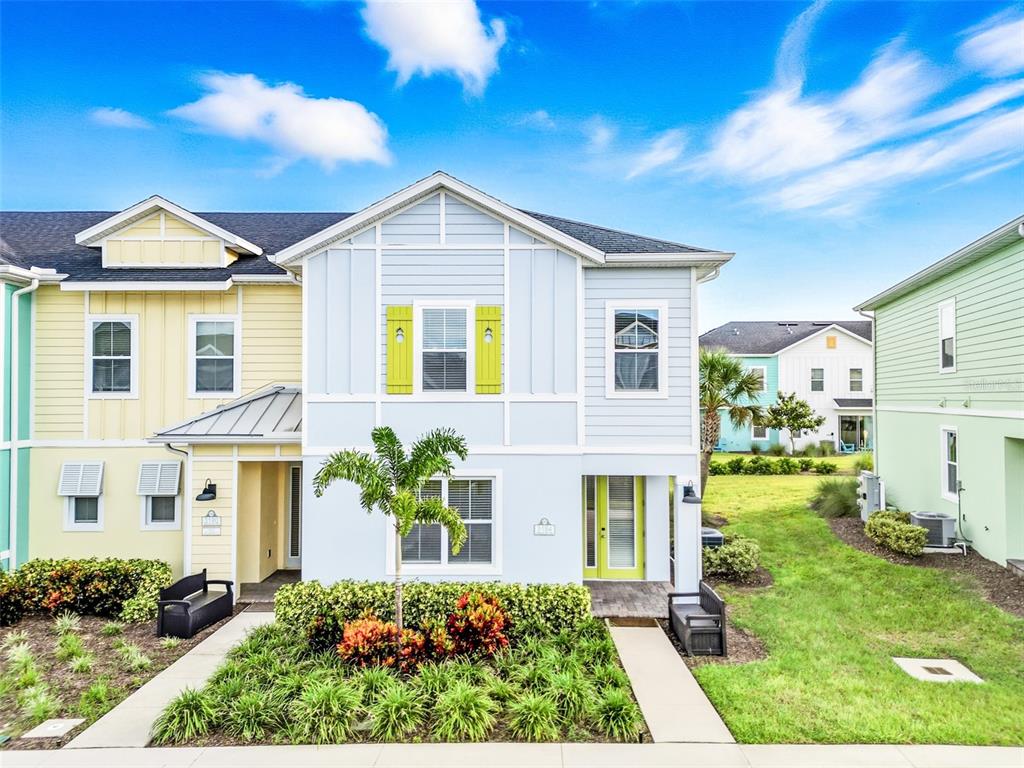 A light blue and yellow townhome with a small front garden and a palm tree — 3184 CARIBBEAN SOUL DRIVE, KISSIMMEE, FL