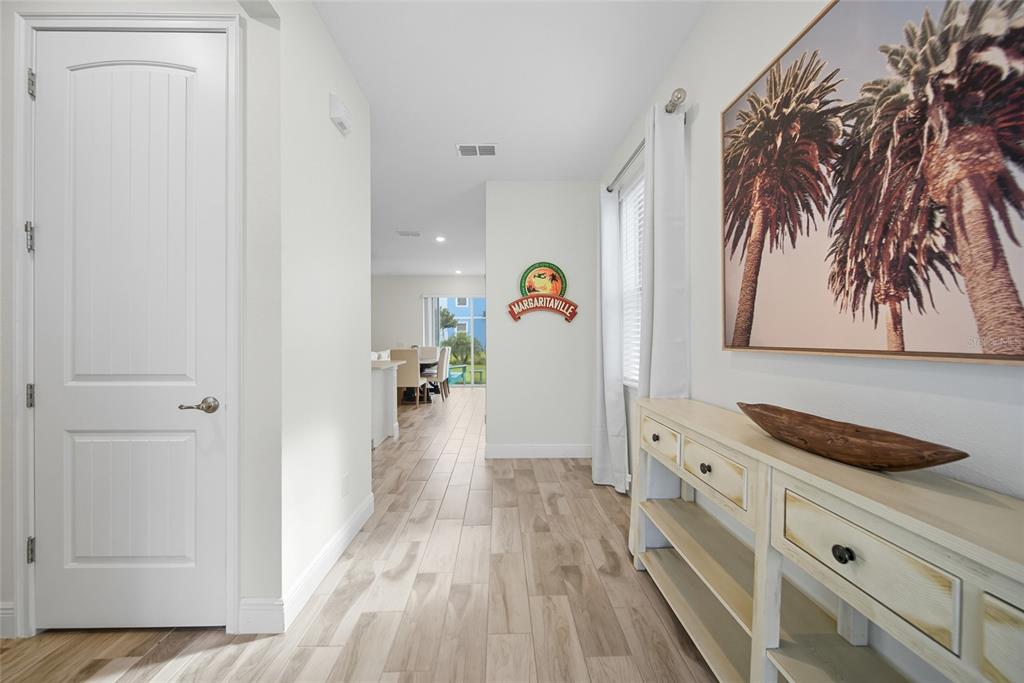 A hallway with wood-look tile flooring leads to a dining area with a sliding door — 3184 CARIBBEAN SOUL DRIVE, KISSIMMEE, FL
