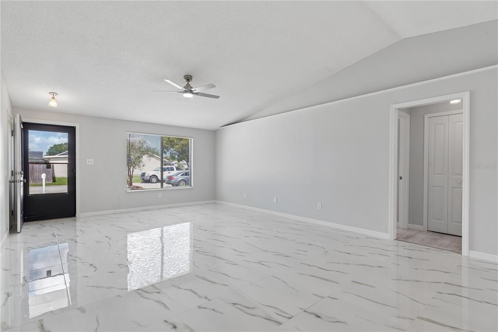 A bright living room features white marble-look tile flooring, light gray walls, and a ceiling fan — 5588 GARDEN GROVE CIRCLE, WINTER PARK, FL