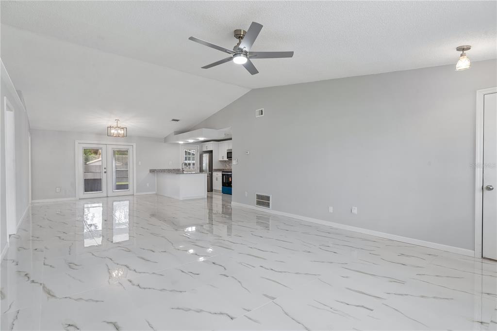 A bright living room features white marble-look tile flooring, light gray walls, and a ceiling fan — 5588 GARDEN GROVE CIRCLE, WINTER PARK, FL