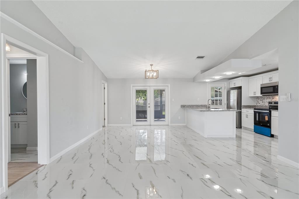 An open-concept kitchen and dining area features white marble-look tile flooring and white cabinetry — 5588 GARDEN GROVE CIRCLE, WINTER PARK, FL