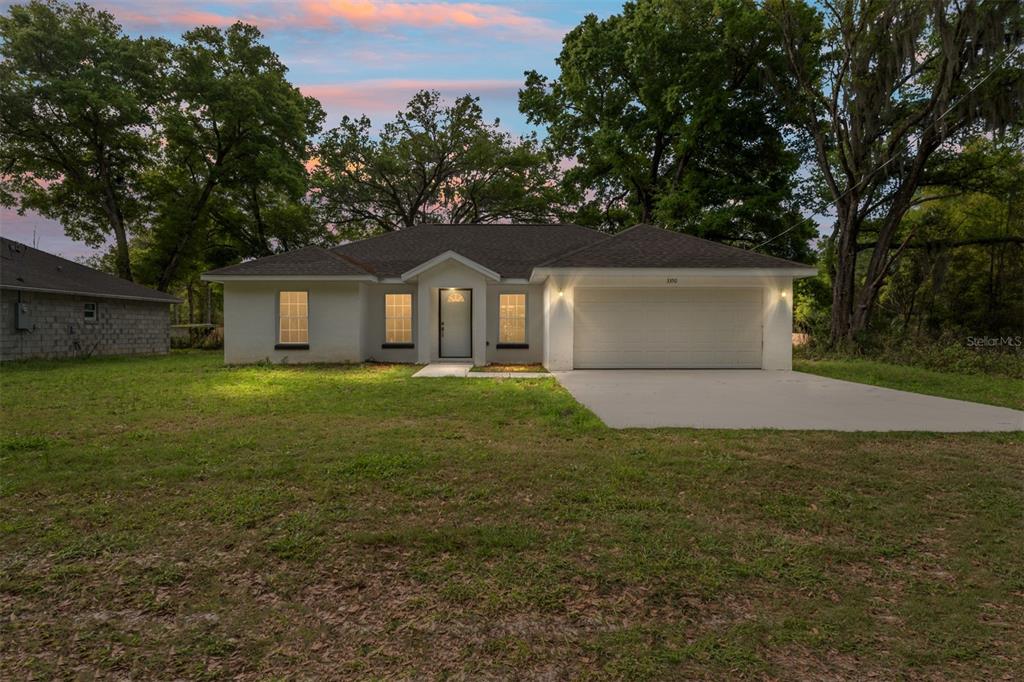 A single-story house with a white exterior, a two-car garage, and a concrete driveway — 3368 SE 142ND, SUMMERFIELD, FL