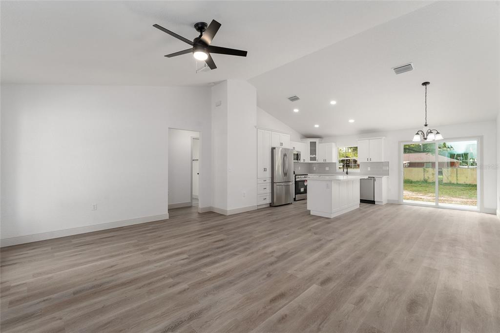 An open-concept kitchen and living area with white cabinets, a center island, and wood flooring — 3368 SE 142ND, SUMMERFIELD, FL