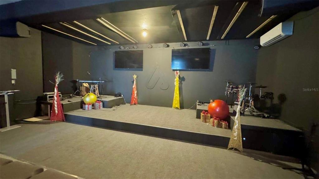 A stage with musical instruments and holiday decorations sits in front of two wall-mounted televisions — 2 56 CARR. #2 BO PALENQUE H-7, BARCELONETA, PR
