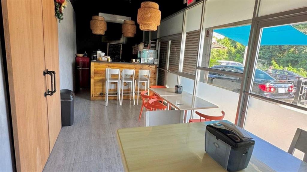 A small cafe interior features a wooden bar, hanging woven lights, and window-side seating — 2 56 CARR. #2 BO PALENQUE H-7, BARCELONETA, PR