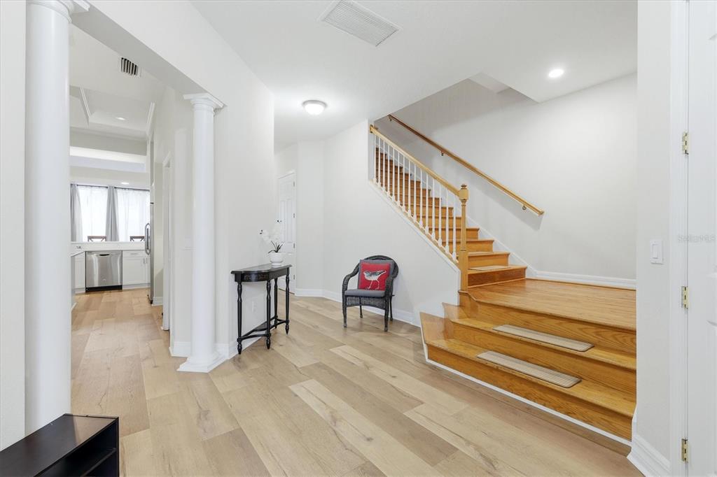 A foyer features light wood flooring, a wooden staircase, and a black accent chair — 3409 54TH DR W UNIT H-103, BRADENTON, FL