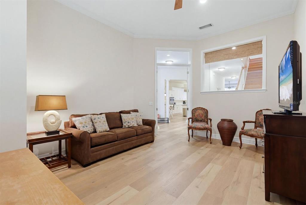 A living room features a brown sofa, two patterned chairs, and light wood flooring — 3409 54TH DR W UNIT H-103, BRADENTON, FL