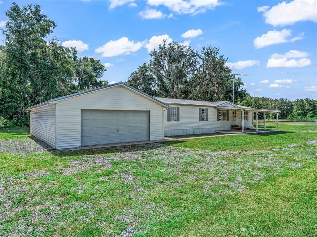 A single-story house with light siding, an attached garage, and a covered front porch — 7363 CR 763, BUSHNELL, FL