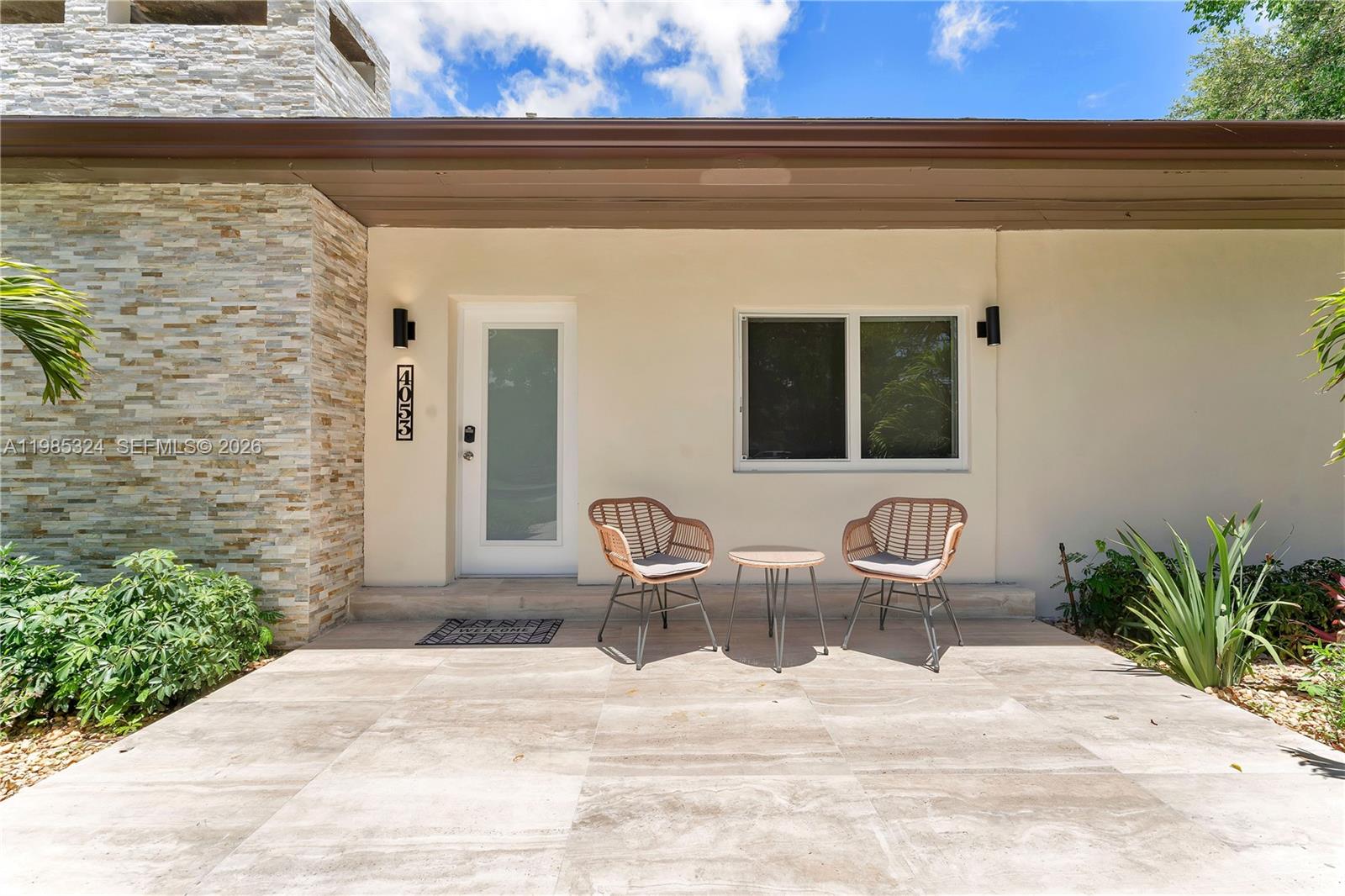 A front patio features two wicker chairs, a small table, and a stone-clad exterior wall — 4053 SW 8th St, Plantation FL 33317, PLANTATION, FL