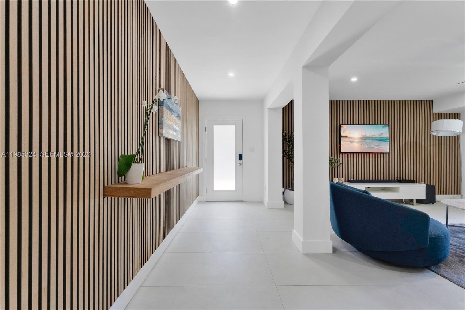 A modern entryway and living area feature white tile floors and wood slat accent walls — 4053 SW 8th St, Plantation FL 33317, PLANTATION, FL