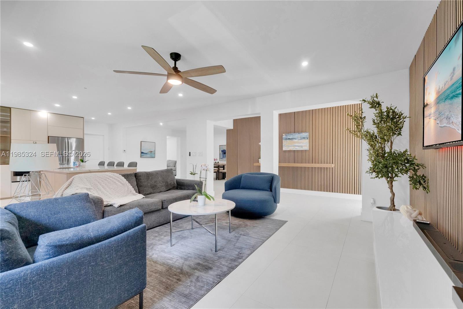 A modern living room features a gray sofa, blue armchairs, and wood-slat accent walls — 4053 SW 8th St, Plantation FL 33317, PLANTATION, FL