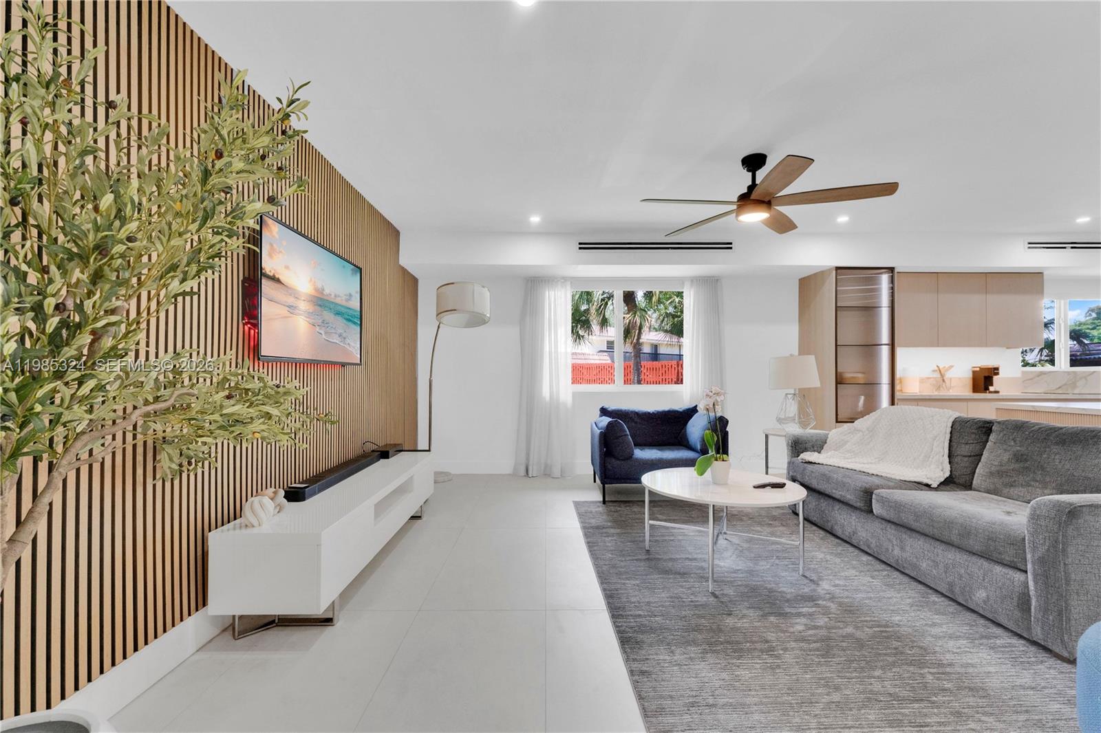 A modern living room features a slatted wood accent wall, gray sofa, and tile flooring — 4053 SW 8th St, Plantation FL 33317, PLANTATION, FL
