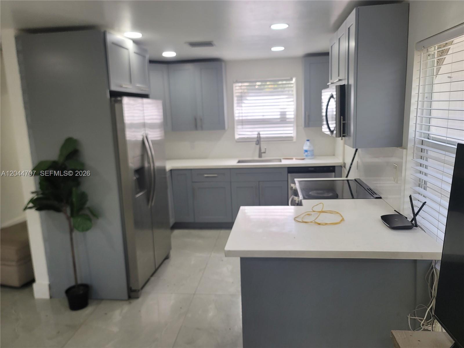 A kitchen features gray cabinets, stainless steel appliances, and white countertops — 512 NW 96th St # B, Miami FL 33150, MIAMI, FL